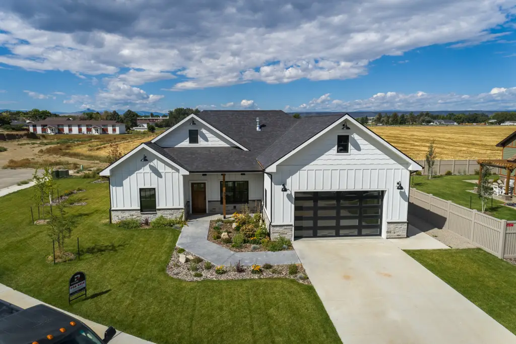 Exterior drone photo of a one-story modern farmhouse home built by Harvell Homes in Powell, Wyoming with finished landscaping featuring the front