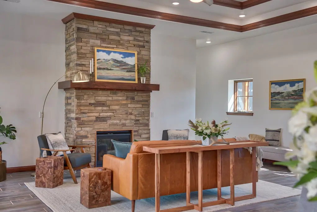 Interior photo of a home built by Harvell Homes in Powell, Wyoming featuring a furnished living room with tray ceiling and floor-to-ceiling stone fireplace
