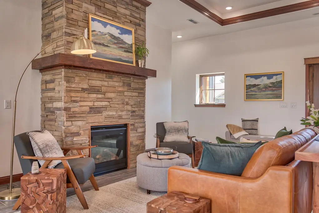 Interior photo of a home built by Harvell Homes in Powell, Wyoming featuring a furnished living room with tray ceiling and floor-to-ceiling stone fireplace