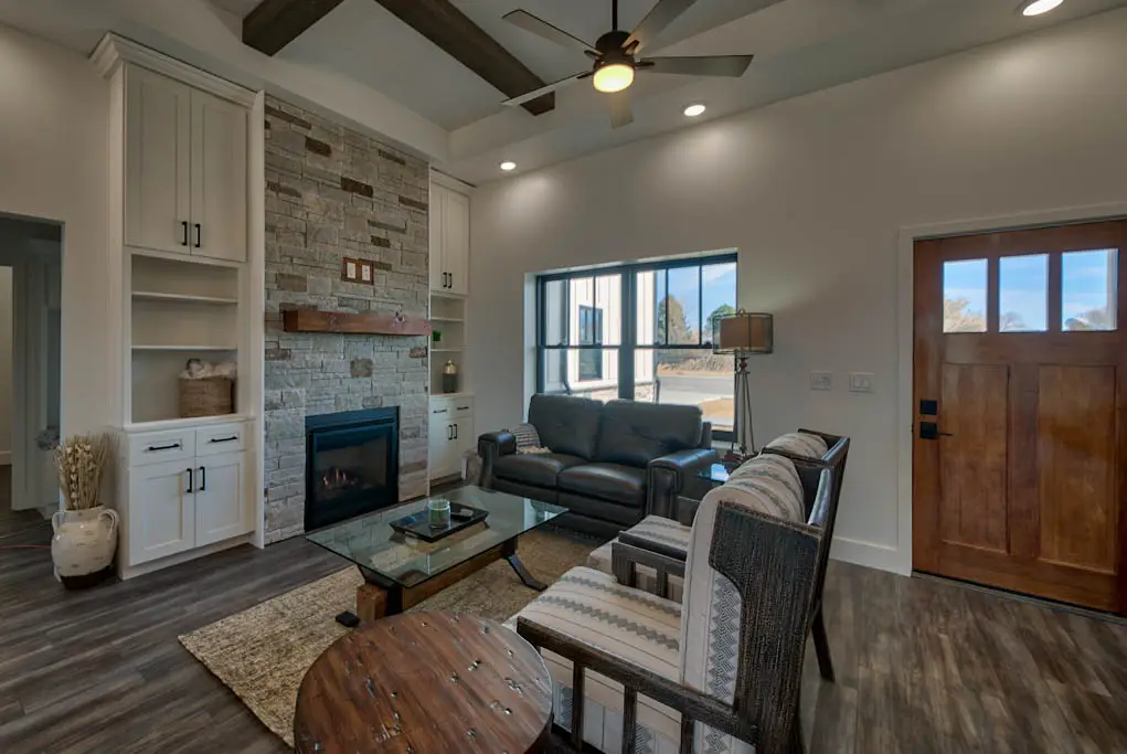 Interior photo of a home built by Harvell Homes in Powell, Wyoming featuring a furnished living room with wood-beam ceiling and floor-to-ceiling stone fireplace
