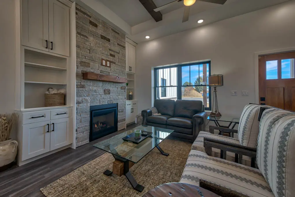 Interior photo of a home built by Harvell Homes in Powell, Wyoming featuring a furnished living room with wood-beam ceiling and floor-to-ceiling stone fireplace