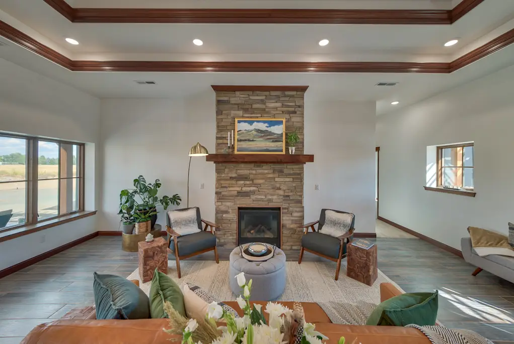 Interior photo of a home built by Harvell Homes in Powell, Wyoming featuring a furnished living room with tray ceiling and floor-to-ceiling stone fireplace