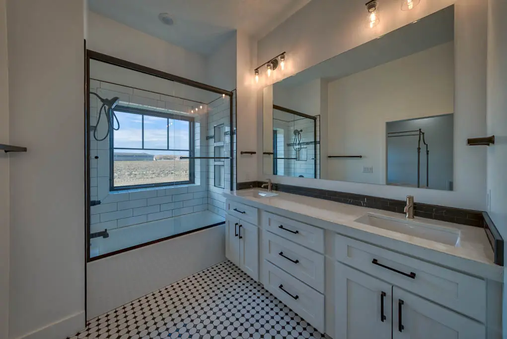 Interior photo of a home built by Harvell Homes in Powell, Wyoming featuring a modern farmhouse bathroom with sliding door bathtub shower and double sinks