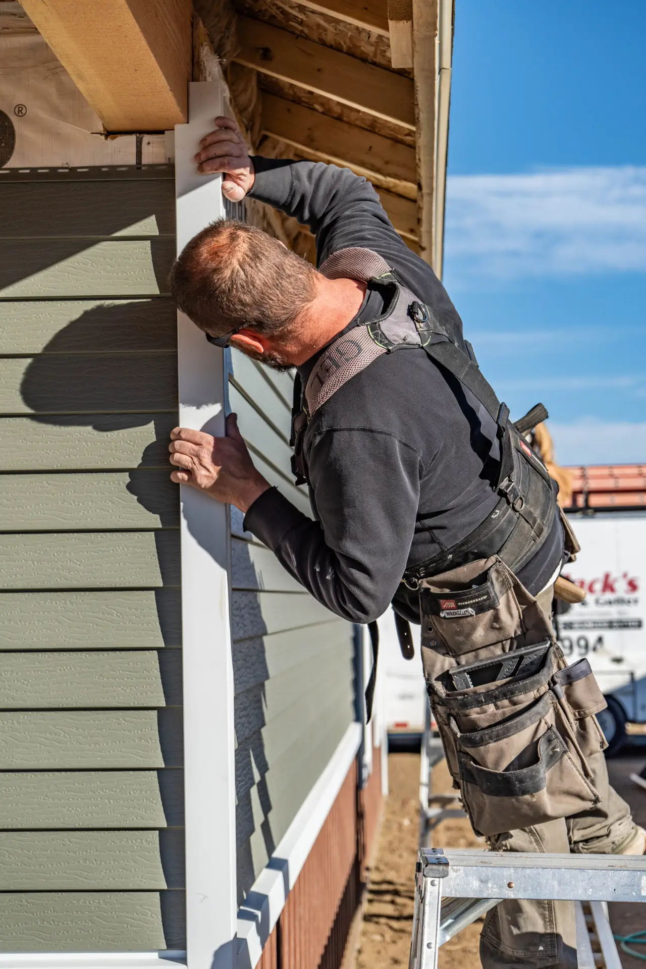 Craftsman installing exterior trim and siding with precision during the construction of a Harvell home.